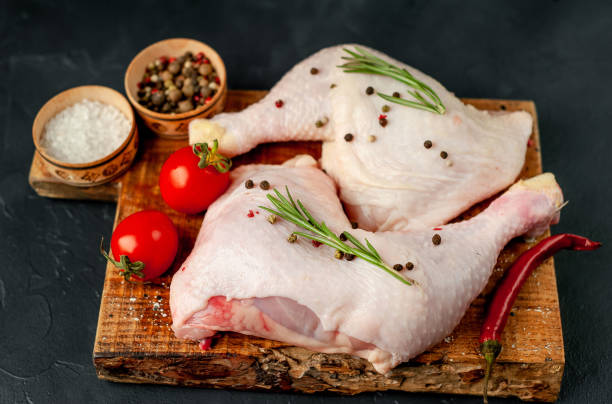 istock Raw chicken legs with spices and herbs ready for cooking on a stone background. 1310303658