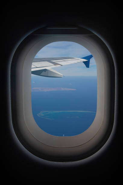 A view from an airplane window, flying over a beautiful beach