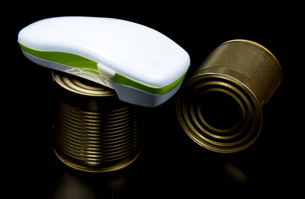 Electric can opener and canned good isolated on black background stock photo