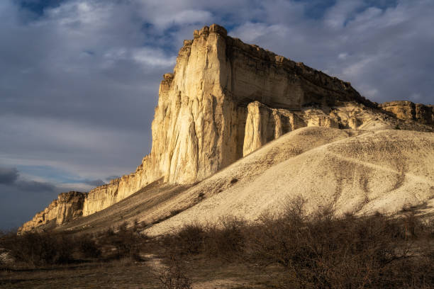 istock Beautiful white mountain peak lit by sun. White clouds and blue sky on background. Epic rock formation 1310308222