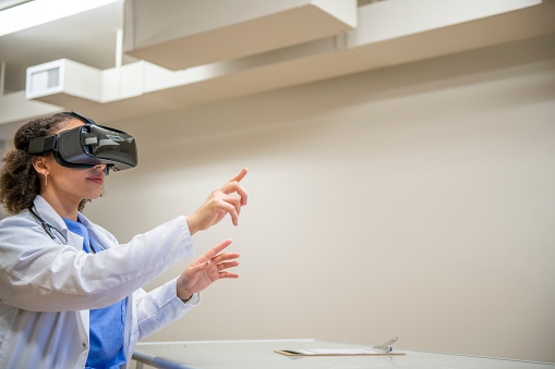 Female medical professional using a virtual reality headset in a clinic to explore a medical case for educational purposes.