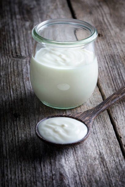 istock Yoghurt pot, wooden table background 1310314352