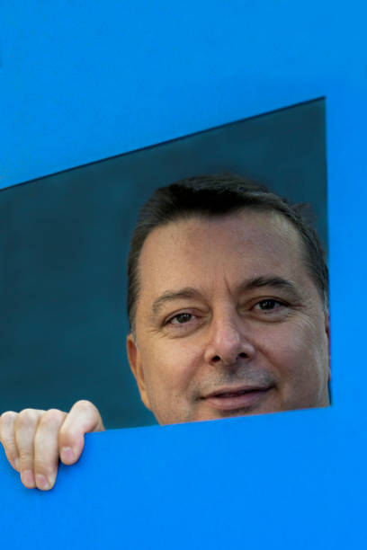 istock Portrait Of Mature Man Looking Though Blue Quadrilateral Frame 1310315357
