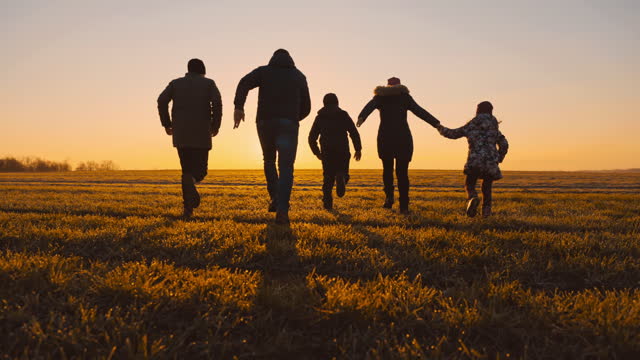 SLO MO WS Family with three kids spending fun time on a meadow at sunset