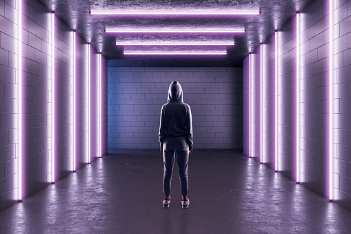 Man standing in a corridor with pink neon lights, concrete floor, brick walls, sport advertising concept