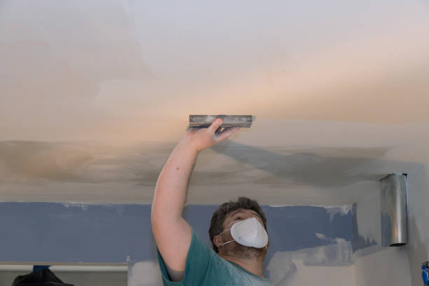 istock Contractor using sand trowel sanding the drywall ceiling during room renovation 1310318303