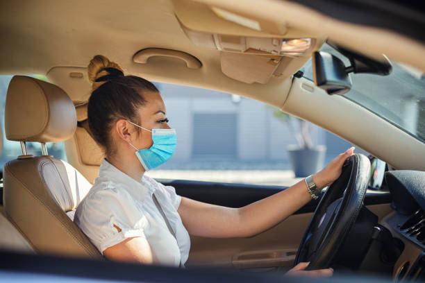 istock Cute young woman with protective mask driving a car 1310319494