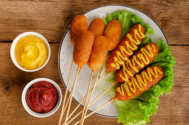 Deep fried corn dogs Deep fried corn dogs with mustard and ketchup on wooden background. American junk food concept. Top view pub table top view stock pictures, royalty-free photos & images