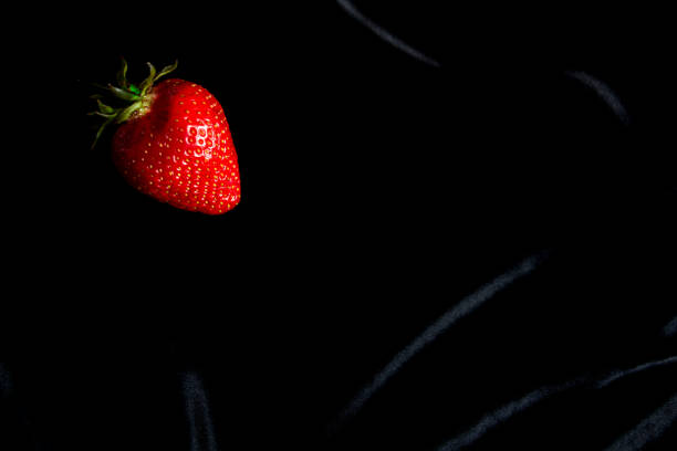 One bright strawberry on a black background, appetizing, beautiful, dietary. Place for text, copy space, flat lay. High quality photo