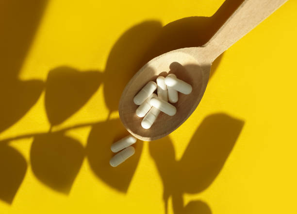 istock wooden spoon, collagen capsules on a colored background 1310326102