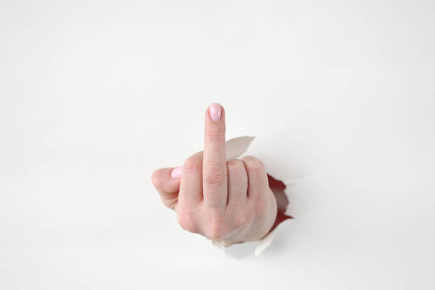 Hand showing middle finger from torn paper. Fuck you system concept