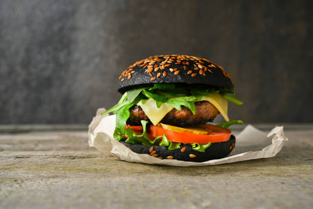 istock Black burger on wooden table on grey background. 1310332813