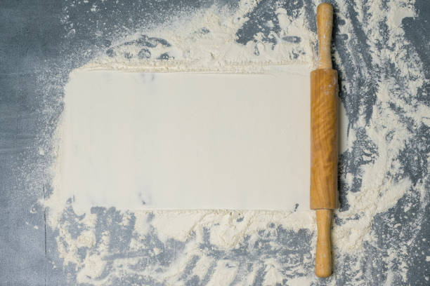 istock Rolling pin and white flour on a dark surface with free space for text . Top view. 1310333426