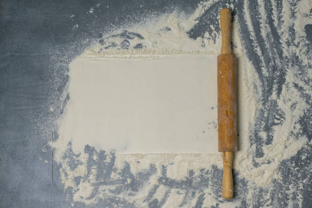 istock Rolling pin and white flour on a dark surface with free space for text . Top view. 1310333430