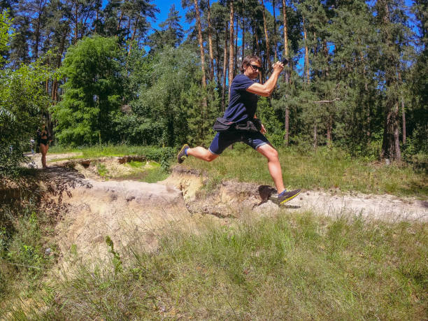 istock Jump. A man with a camera in his hands jumps over a ravine. 1310335801