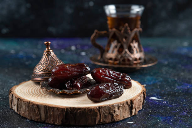 istock Hot tea behind of dry dates on blue background 1310335821
