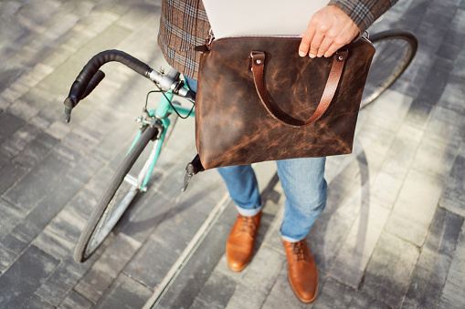 High-angle view of an unrecognizable man placing his laptop into a leather bag.