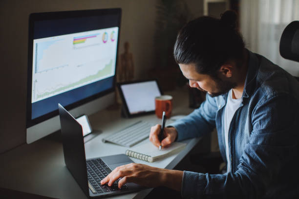 Young man using desktop pc at desk in home office Young man working from home. Business accounting concept, Business man using calculator with computer laptop, budget and loan paper in office. Unrecognizable person using his laptop and trading Bitcoin. Bitcoin / Cryptocurrency concept. smart phone technology lifestyles chain stock pictures, royalty-free photos & images