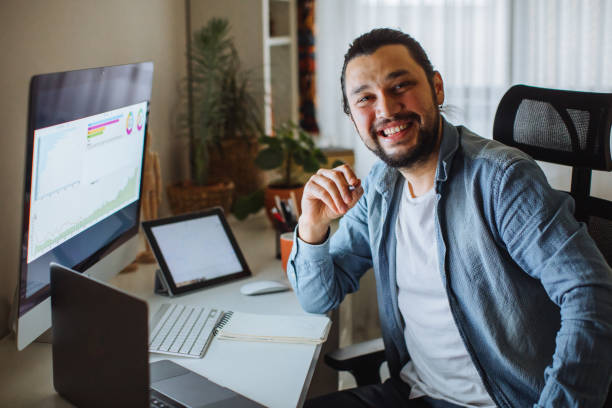 istock Young man using desktop pc at desk in home office 1310342608