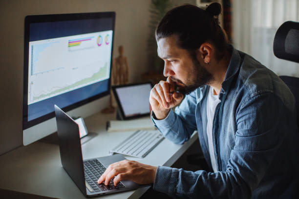 Young man using desktop pc at desk in home office Young man working from home. Business accounting concept, Business man using calculator with computer laptop, budget and loan paper in office. Unrecognizable person using his laptop and trading Bitcoin. Bitcoin / Cryptocurrency concept. smart phone technology lifestyles chain stock pictures, royalty-free photos & images