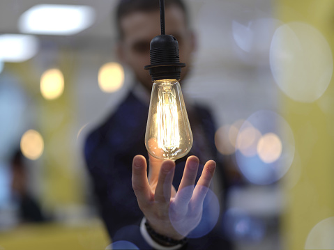 businessman at office holding a hand around light bulb representing concept of business solutions idea and green energy