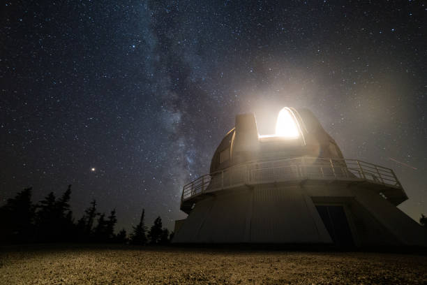 light coming from the top of an observatory bright red light coming from a construction on the mountain with the milky way in the background Observatory stock pictures, royalty-free photos & images