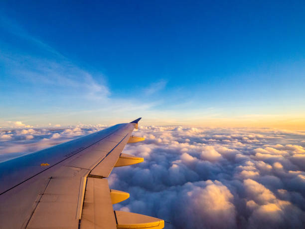 airplane wing in the sky on a sunset view of the window of an aircraft to a view of the right side wing on a sunrise over the clouds planes flying overhead stock pictures, royalty-free photos & images