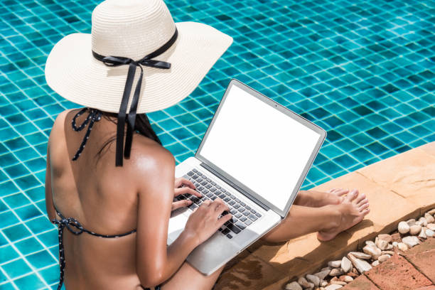 istock Asian Woman working on laptop computer sitting at poolside 1310358573
