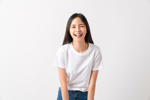 Studio shot of cheerful beautiful Asian woman in white t-shirt and stand on white background.