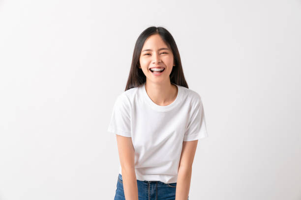 Studio shot of cheerful beautiful Asian woman in white t-shirt and stand on white background. Studio shot of cheerful beautiful Asian woman in white t-shirt and stand on white background. asian culture stock pictures, royalty-free photos & images
