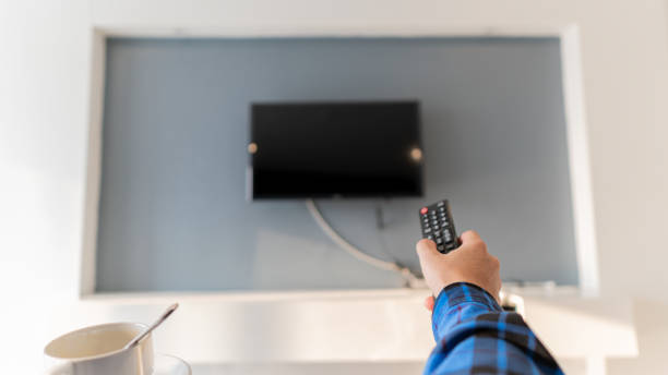 istock A young man with a remote control and a coffee mug is watching TV in the room. 1310367326