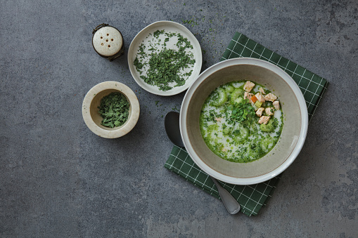 Salmon soup with potato, fennel,celery and green herb oil. Flat lay top-down composition on concrete background. Horizontal image with copy space.