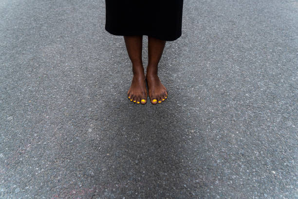 Bare-footed black ethnic woman standing on the street