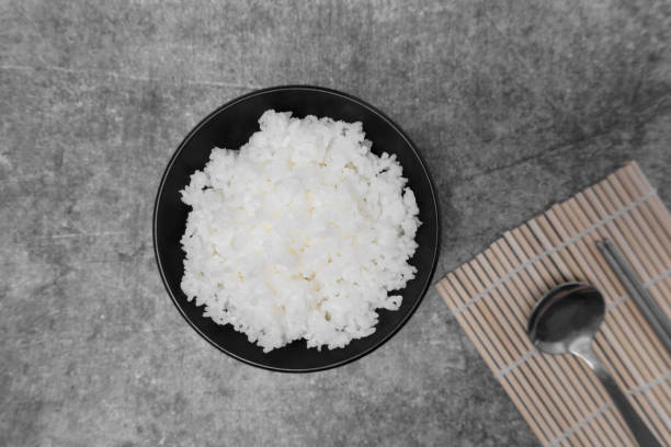 vista superior arroz blanco al vapor en tazón negro. - cooked still life close up rice fotografías e imágenes de stock