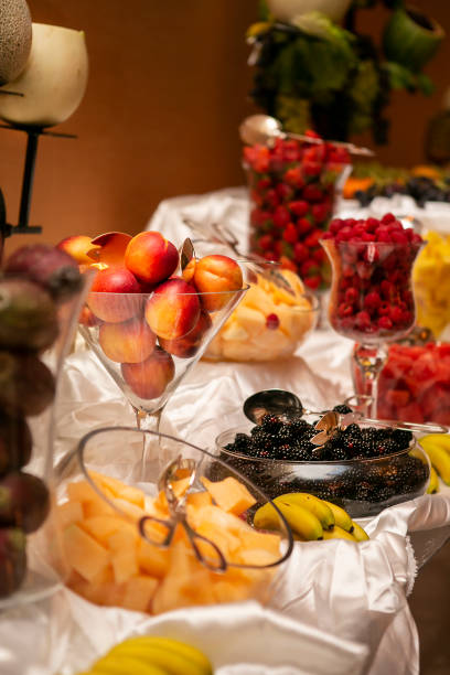 mesa atendida llena de fruta en recipientes de vidrio con melocotones, peras prickely, fresas, moras, melón y plátanos para una ceremonia de boda - prickley pear cactus fotografías e imágenes de stock