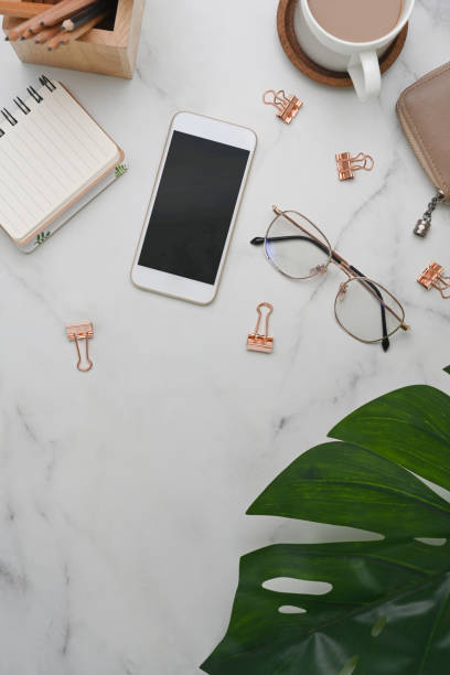 istock Female workplace with smart phone, coffee cup, notebook and stationery on white desk. 1310382673
