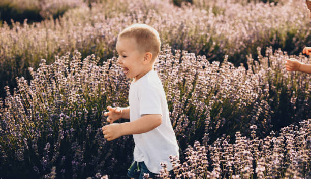 istock Charming caucasian small boy running through a lavender field smiling in a white shirt 1310384473