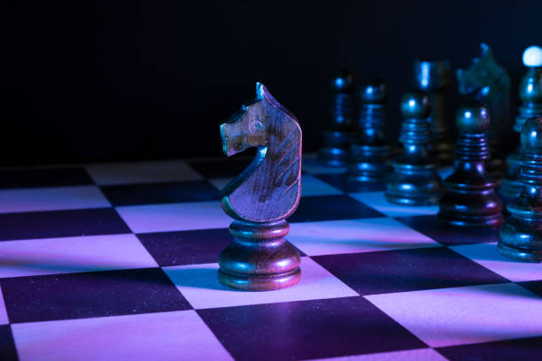 istock Knight chess figures on a chessboard. Dark background, neon studio lights 1310389601