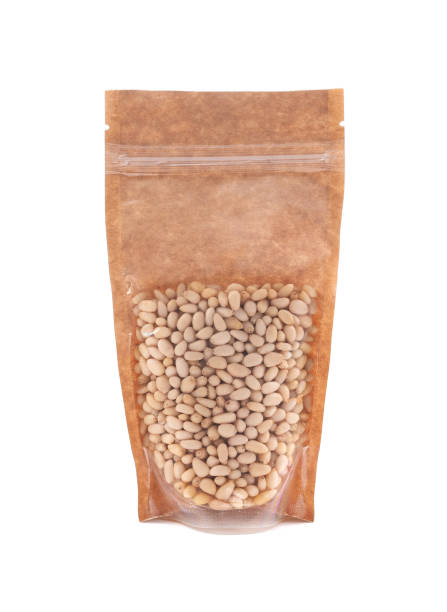 istock Peeled pine nuts in a brown paper bag. Doy-pack with a plastic window for bulk products. Close-up. White background. Isolated. 1310393111