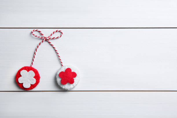 Traditional martisor on white wooden background, top view with space for text. Beginning of spring celebration