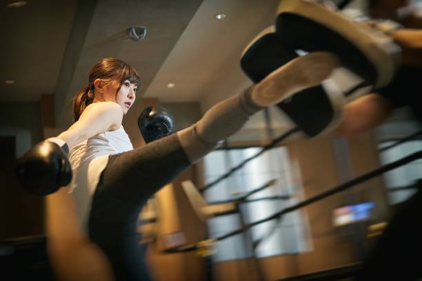 mujer asiática aprendiendo kickboxing de un entrenador personal - kickboxing fotografías e imágenes de stock