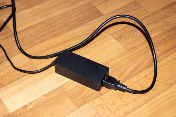 Black extension cord with button and wires on wooden floor