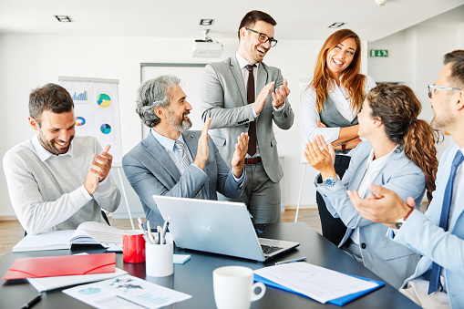 Successful businesspeople applauding to colleague during a meeting in an office. Business concept