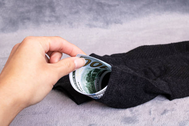 istock Dollars in sock and hand on gray background 1310396578