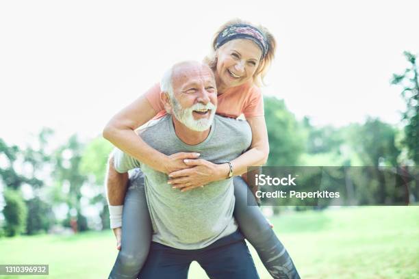 Outdoor Senior Fitness Woman Man Lifestyle Active Sport Exercise Healthy Fit Retirement Love Fun Piggyback Stock Photo - Download Image Now