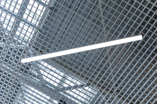 Photo of LED lighting lamp on the ceiling of an commercial building. Grid ceiling make nice architectural interior false ceiling view or design for shopping mall and office building
