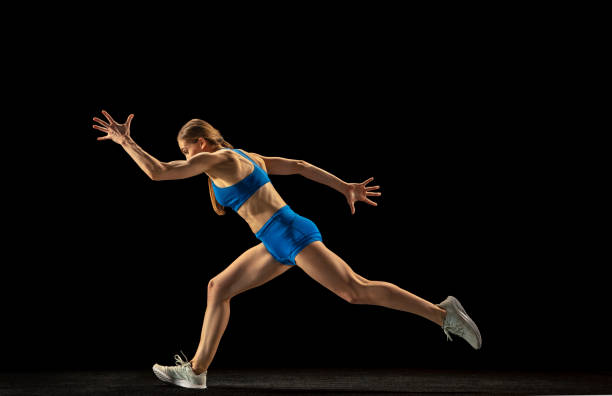 istock Sportive woman, track athlete training isolated over black studio background. 1310399468
