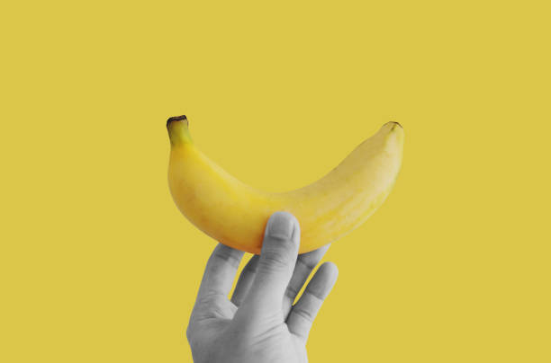istock Hand holding banana, on yellow background 1310410351