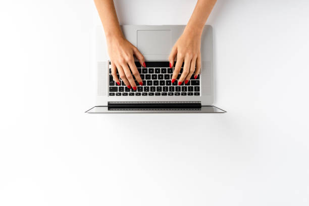 istock Overhead shot of woman’s hands working on laptop isolated on white background. Office desktop. Flat lay 1310410902