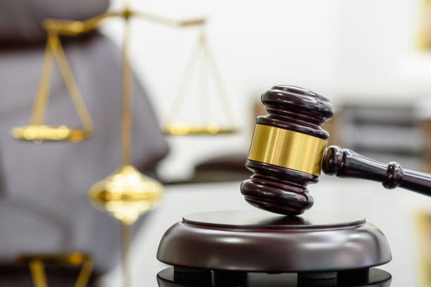 un juez de madera dio o un martillo de madera y una caja de resonancia utilizada por una persona del juez en un escritorio en un tribunal con una escala de latón borrosa de la justicia detrás. - courthouse fotografías e imágenes de stock